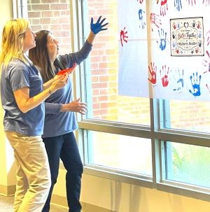 Employees with painted hands on community care poster
